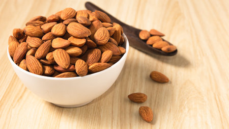 Almond nuts in a white bowl on wooden background, selective focus.front view.copy space.の写真素材