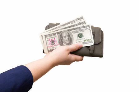 The hand of a white female adult in a blue shirt is holding 3 hundred dollar bills and wallet on an...