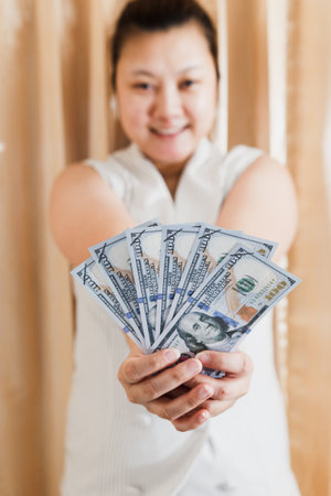 The right and left hand of a white woman showing a mock-up hundred dollar banknote for shopping. selective focus.の写真素材