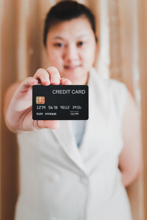 The right hand of a white woman showing a mock-up credit card for shopping. selective focus.の写真素材