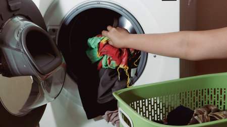 Close-up of a woman's hand putting dirty clothes into the washing machineの写真素材