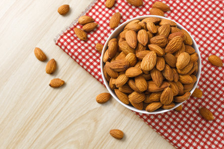 Almond nuts in white bowl on ra red checkered cloth background,top view,flat lay,top down,selective focus.の写真素材