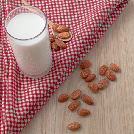almond milk in glass and spoon with nuts are around on red cloth on wood background. selective focus.top view, top-down, flat lay.の写真素材