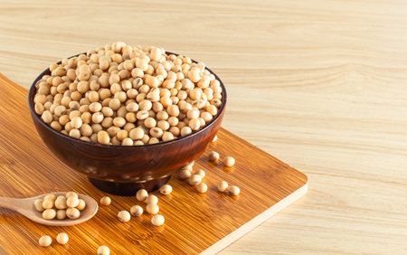 soybean in a bowl with wooden chopping board and spoon on wooden background, front view, selective focus.の写真素材
