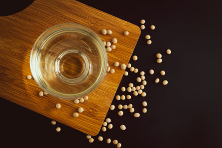 soybean and bowl with oil on a wooden cutting board on black background, top view, flat lay, top-down, selective focus.copy space.の写真素材