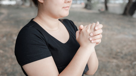 An adult whose hand is prayed on the dark background.Respect for belief in religion and God. front...
