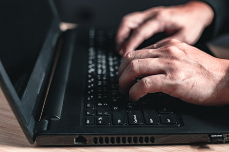 close up hand of businessman sit sideways using and typing laptop computer.