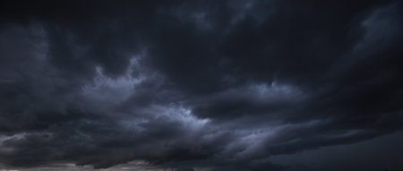 The dark sky with heavy clouds converging and a violent storm before the rain.Bad or moody weather sky and environment. carbon dioxide emissions, greenhouse effect, global warming, climate change.の写真素材
