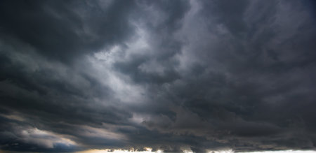 Dark sky with heavy clouds converging and a violent storm before the rain.