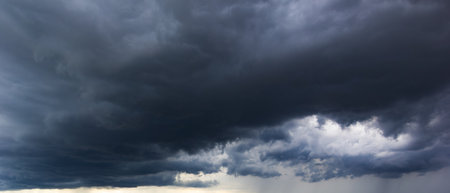 The dark sky with heavy clouds converging and a violent storm before the rain. Bad or moody weather sky and environment.の写真素材