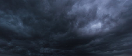 The dark sky with heavy clouds converging and a violent storm before the rain. Bad or moody weather sky and environment.の写真素材