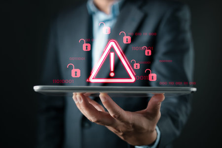 A person holds a tablet displaying red warning icons and open padlocks, symbolizing cybersecurity...