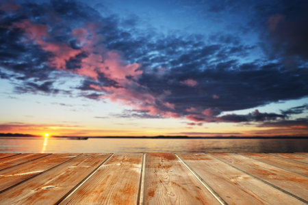 Empty top of wooden table and view of sunset or sunrise background. For product display.の写真素材