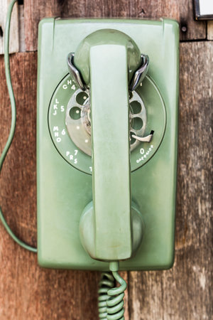 close up old green telephone on wood board wall