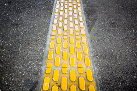 the yellow braille block on asphalt walkway