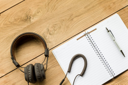 top view of notbook and headphone on wooden background