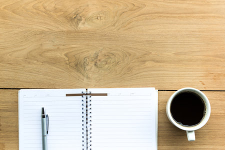 coffee cup with notebook on wooden table backgroundの写真素材