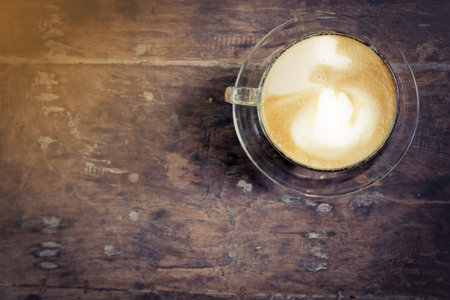 cup of latte coffee on wood table, vintage tone
