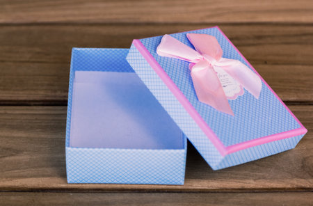 open blue gift box with pink bow on wood table