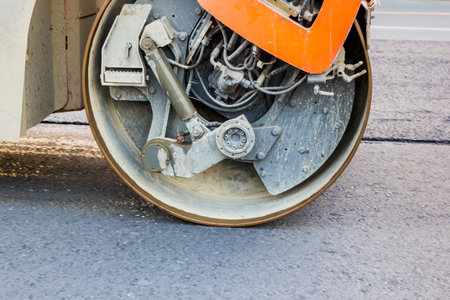 orange road roller working on the new asphalt roadの写真素材