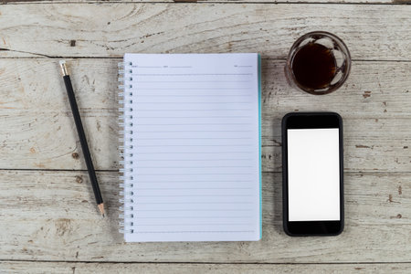 notebook coffee smartphone and pencil on wood table, top viewの写真素材