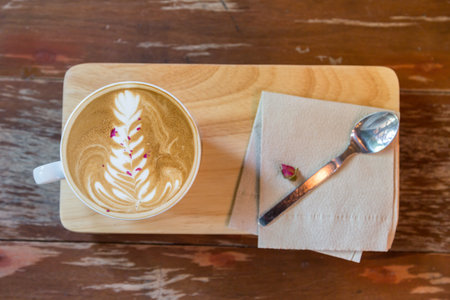 cup of latte coffee and spoon on wood plate, top view