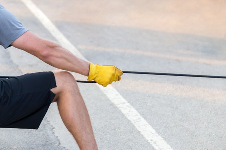 man pulling the black rope with yellow glove