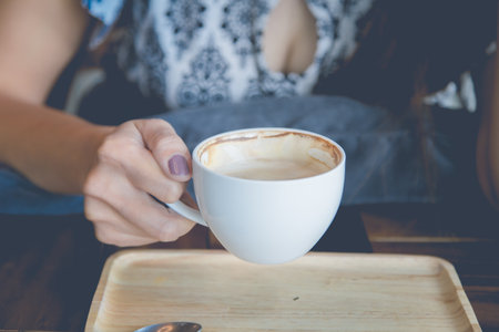 woman hand holding cup of coffee in the cafe, vintage toneの写真素材