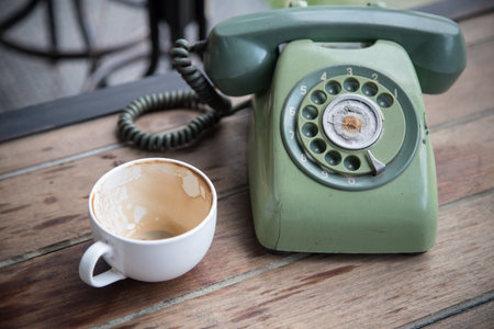 old green telephone and coffee cup after drink on tableの写真素材