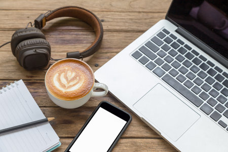 office stuff with laptop coffee cup notepad smartphone and headphone on wood tableの写真素材