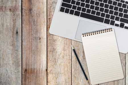 laptop notepad and pencil on wood table backgroundの写真素材