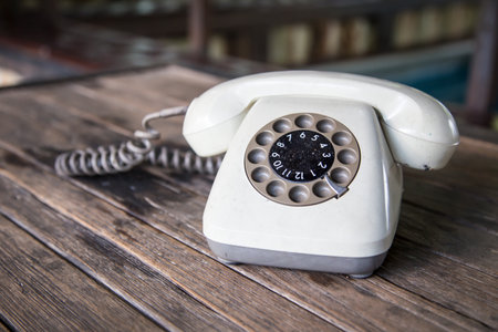 old white rotary telephone on wood tableの写真素材