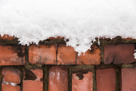 melting snow on old red brick wall