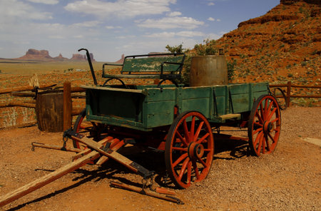 Old farm wagon in front of the fantastic shapes of the vast sandstone buttes of Monument Valley, part of the Colorado Plateau in the Navajo Nation Reservation, from Gouldings Lodge, Utah, USAのeditorial素材
