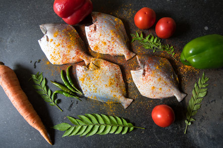 Marinated fresh fish with vegetables on a black background.