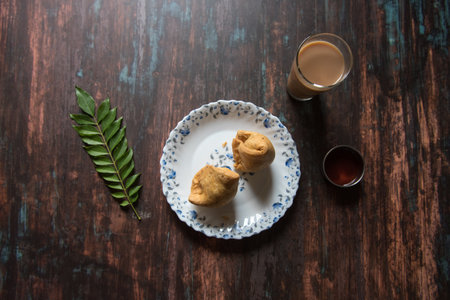 Top view of  Indian snack samosa and tea along with condiments on a background