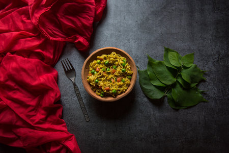 Top view of ready to eat instant noodles in a bowl on a dark background.
