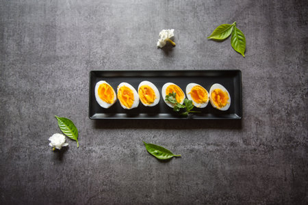 Top view of slices of boiled eggs arranged on a black platter with use of selective focus.の写真素材