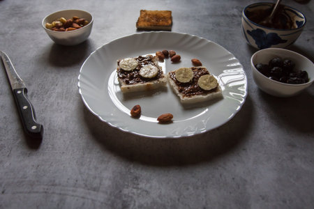 Healthy breakfast food ingredients bread, peanut butter, bananas, almonds, nuts, dry fruits milk. Concept of wholesome and healthy food. Close up.の写真素材