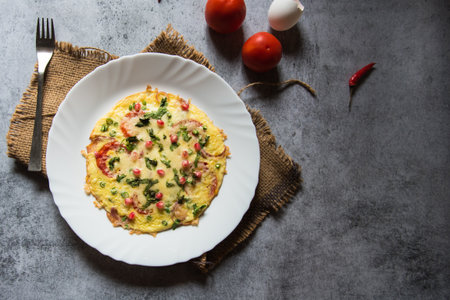 Cheese tomato omelette or Spanish omelette prepared with a base of egg with additional ingredients of cheese, pepper, onion, garlic and tomato. Top view.の写真素材