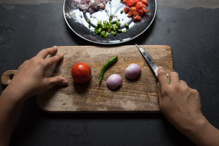 Hands of a lady holding a knife preparing to chop vegetables with use of selective focusの写真素材