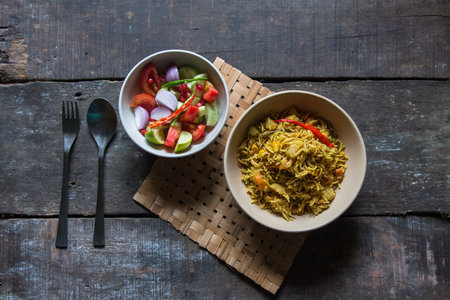Indian vegetable pulao or veg biryani prepared with vegetables, basmati rice and mix of flavoured spices. Top view. Generally served with freshly cut salad condiments.の写真素材