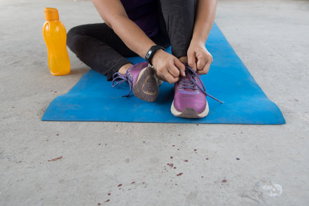 A woman tying jogging shoes getting ready for exercise and fitness workout with use of selective...
