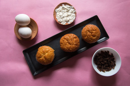 Top view of muffins in a tray along with ingredients on a background.