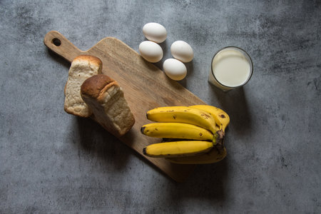Breakfast food items milk, bread eggs and bananas on a background with use of selective focus