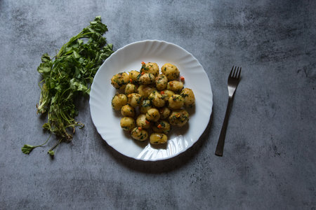 Dum aloo or fried baby potatoes tossed in oil in a white plate. Top view.の写真素材