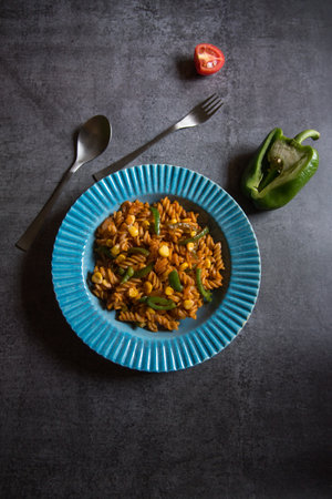 Vegetable spiral pasta served in a blue bowl on a dark background. Top view, selective focus.の写真素材