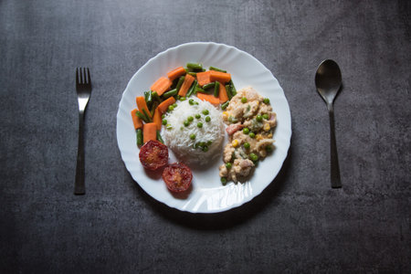 White rice and continental chicken along with condiments served in a plate on a background. Top view, selective focus.の写真素材