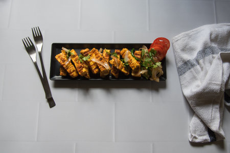 Tandoori grilled paneer or cottage cheese cubes with veggies in a tray. Top view, selective focus.の写真素材