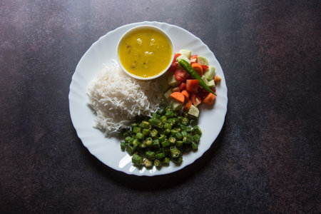 Healthy Indian vegetable thali of rice, boiled vegetables, salad and dal. Top view, selective focus.の写真素材